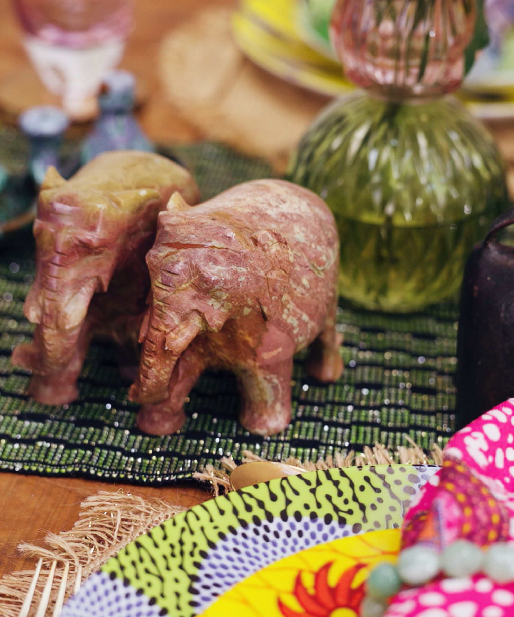 Elephant ornaments on a table laid with bright plates and linens