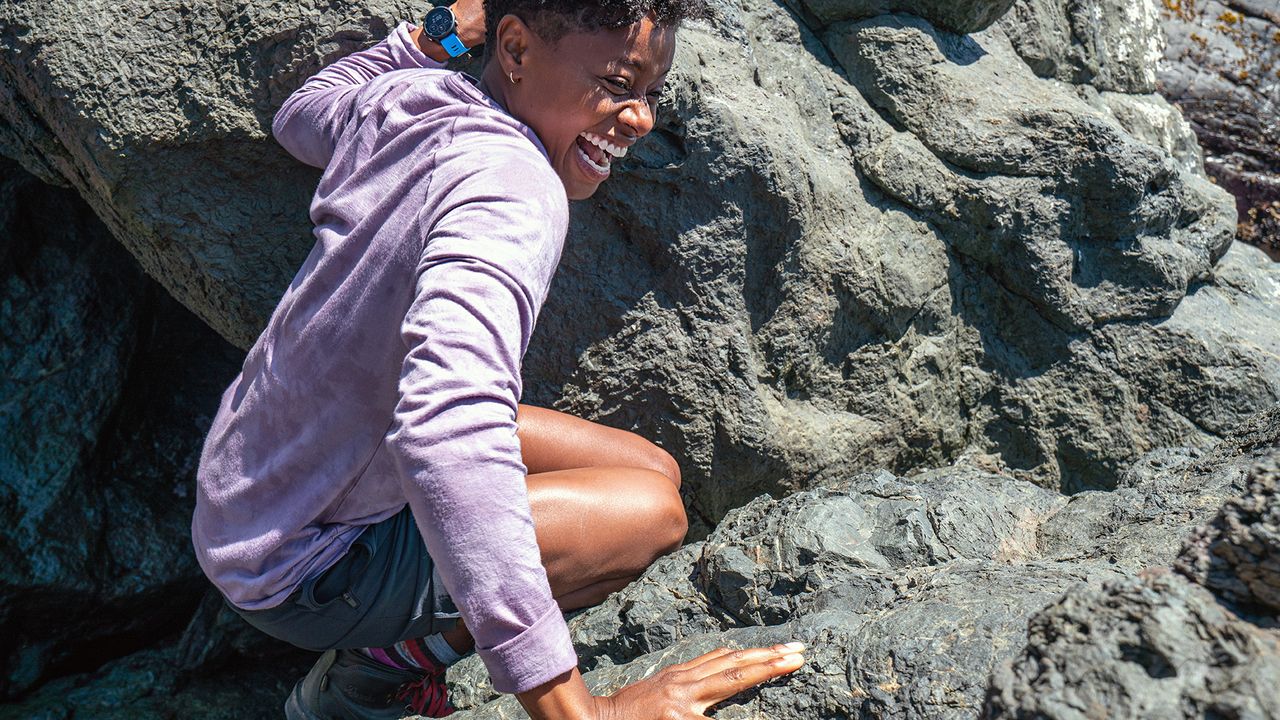 Woman wearing the Smartwool Merino 150 base layer while scrambling over some rocks