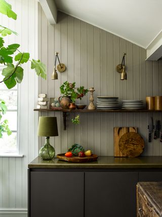 a small green kitchen with a lamp on the countertop