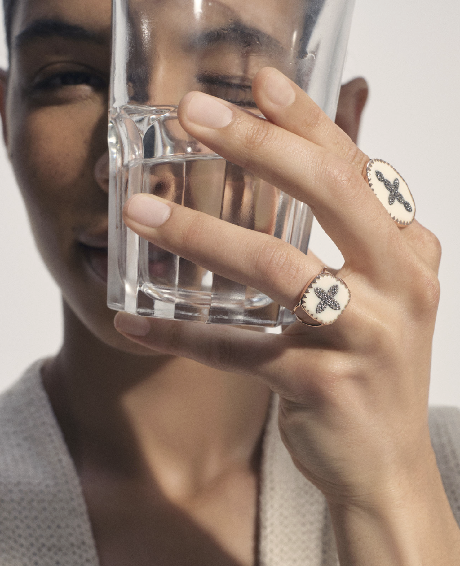 Pascale Monvoisin model wears two cross rings holding glass of water