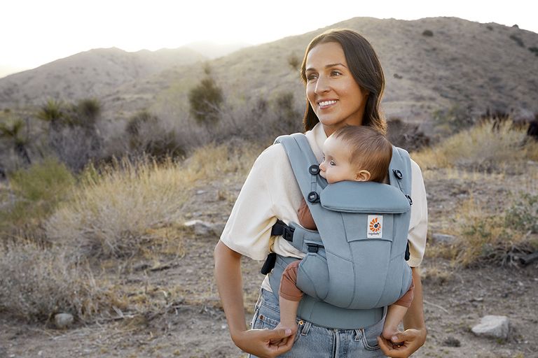 A woman carrying a baby on her chest in the Ergobaby Omni Dream baby carrier - one of the best baby carriers