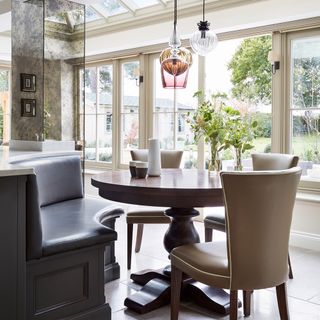 Built-in wooden seating dining table in a conservatory with pendant lights