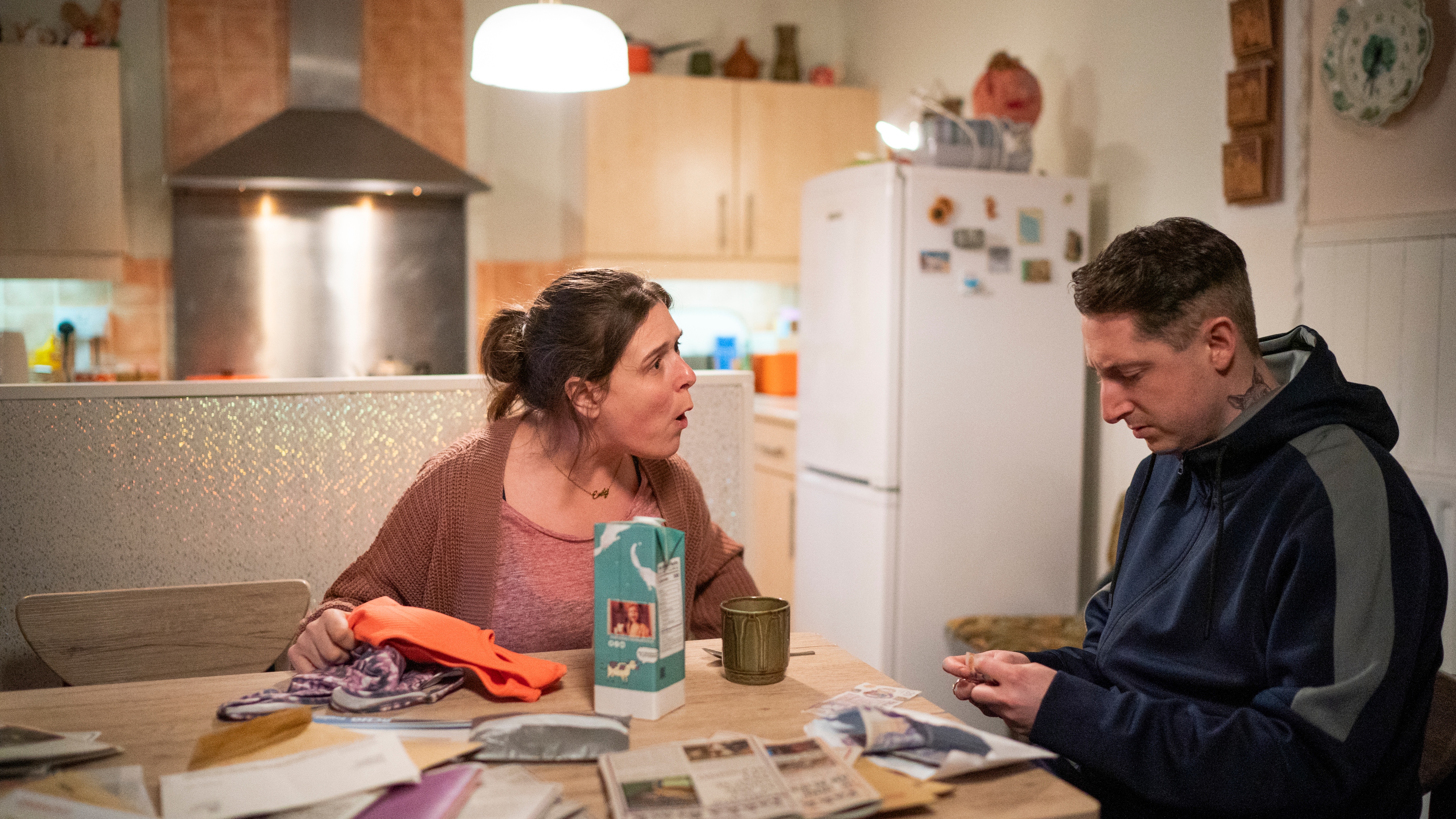 Emily and Ewen chat at her kitchen table in Pushers