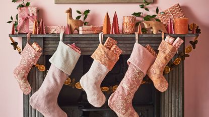 Pink stockings hung from a black fireplace with strings of orange slices
