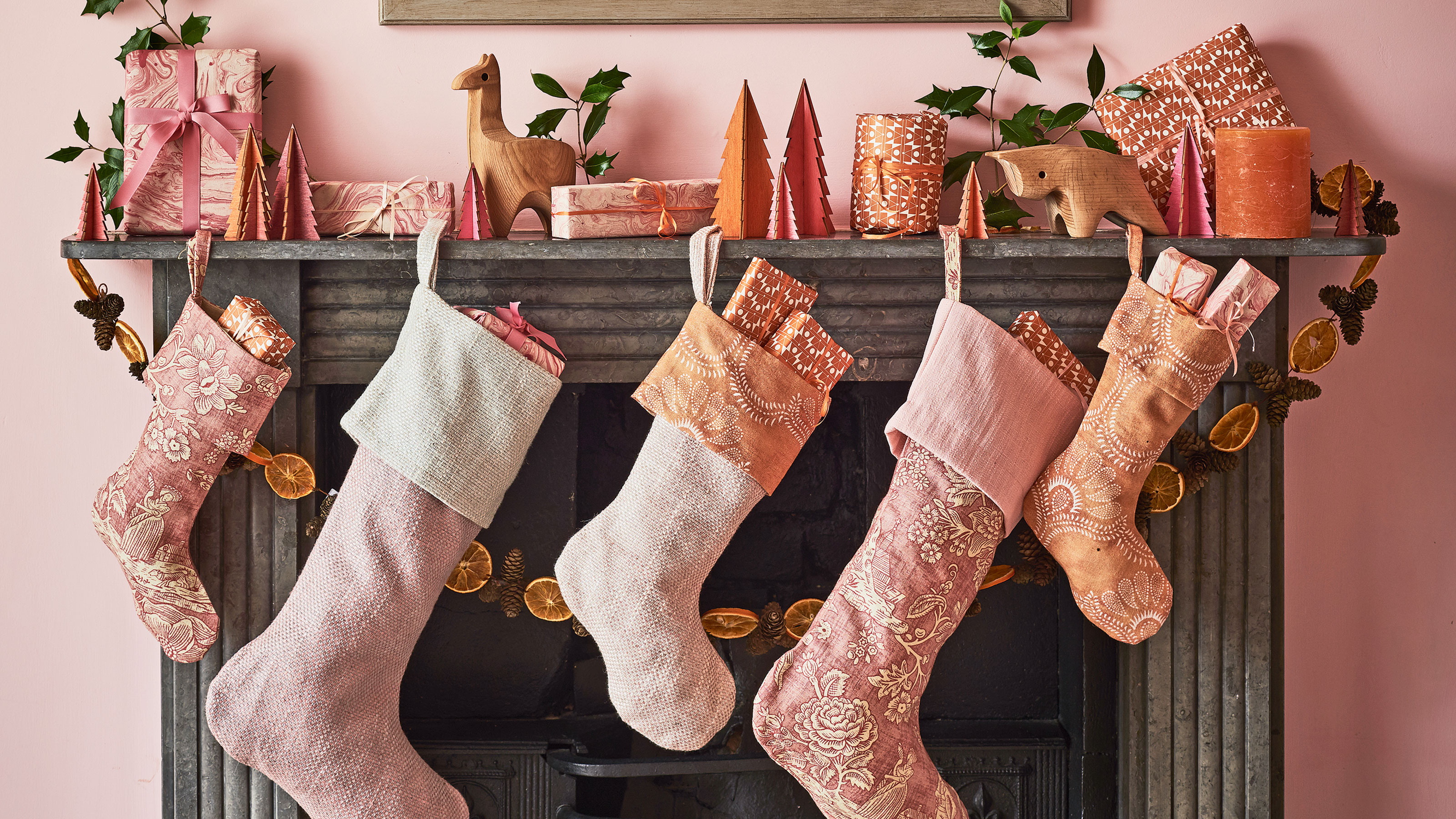 Pink stockings hung from a black fireplace with strings of orange slices