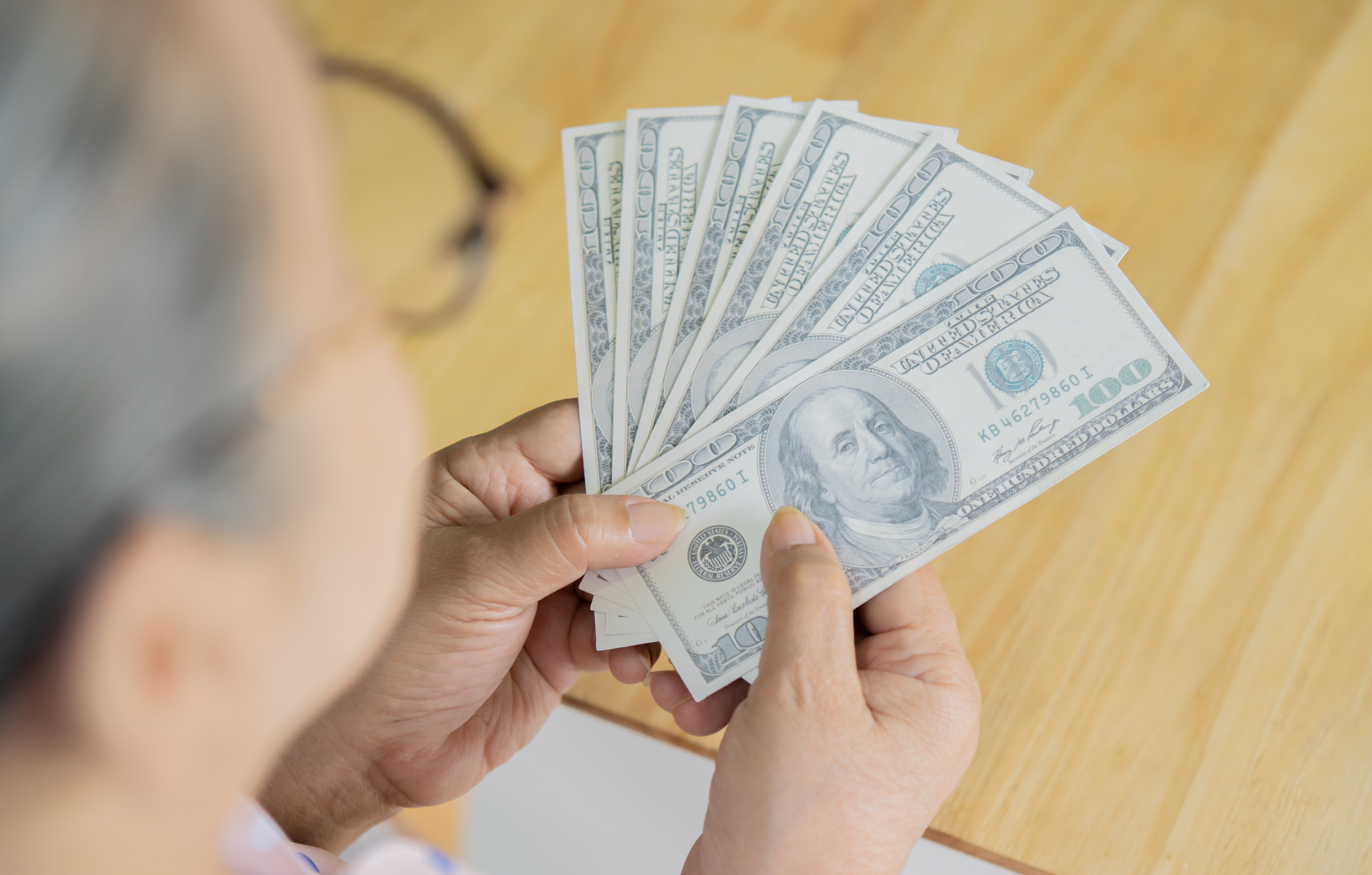 a person counting one hundred dollar bills
