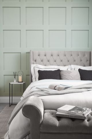 A transitional bedroom with pale green wallpaper