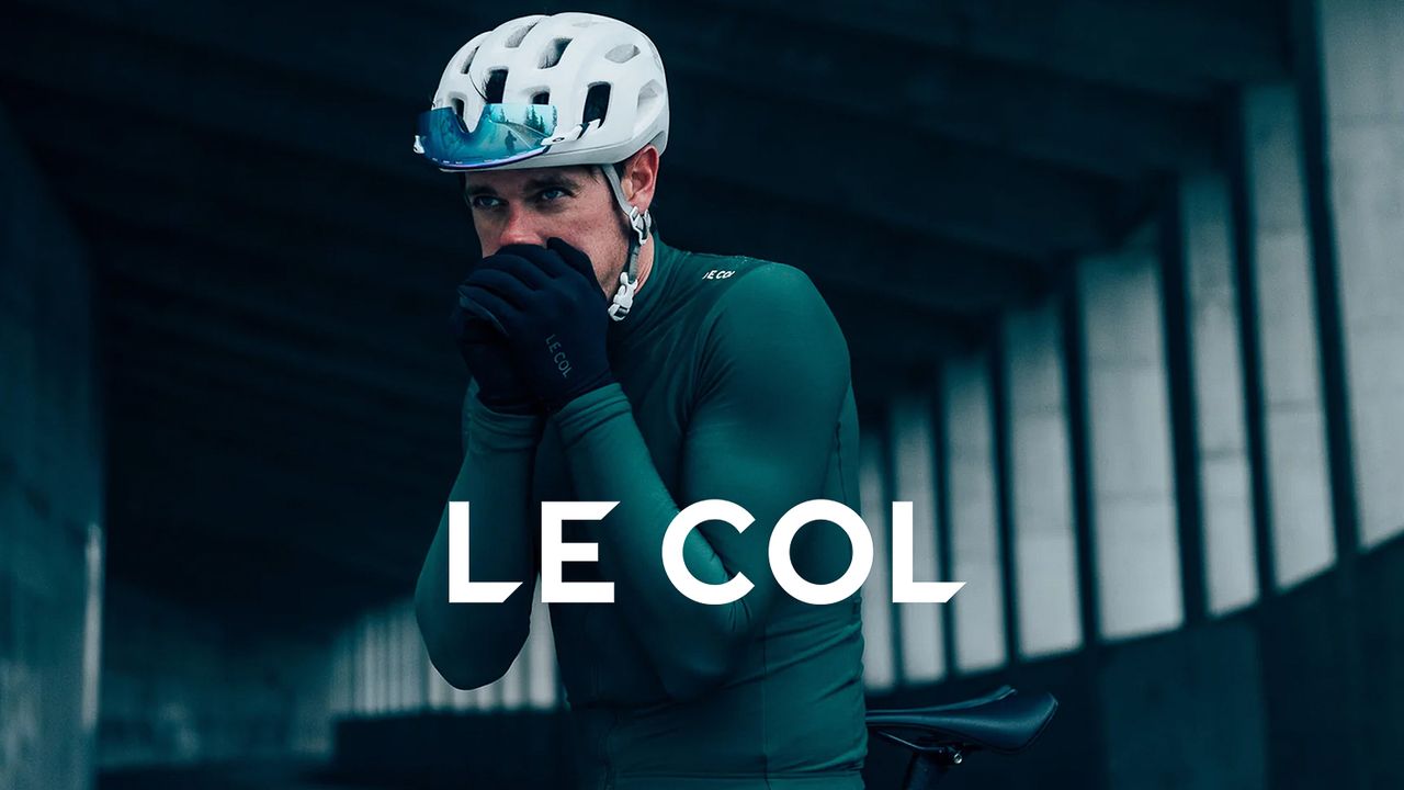 Rider blowing in his hands while wearing Le Col apparel and Le Col overlay logo