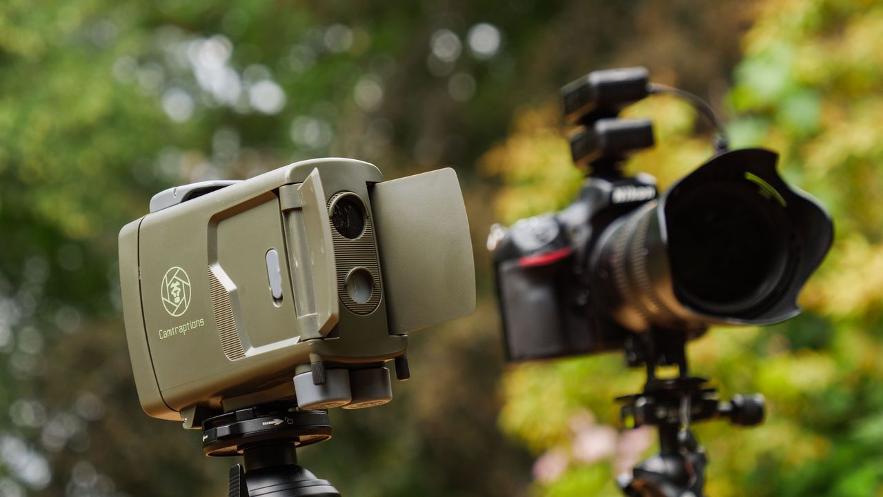 Camtraptions Camera Trap device outdoors alongside a Nikon DSLR camera