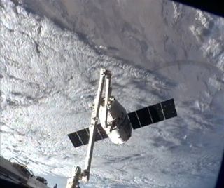SpaceX Dragon capsule at the International Space Station with cloud-covered Earth in the background on March 3, 2013.