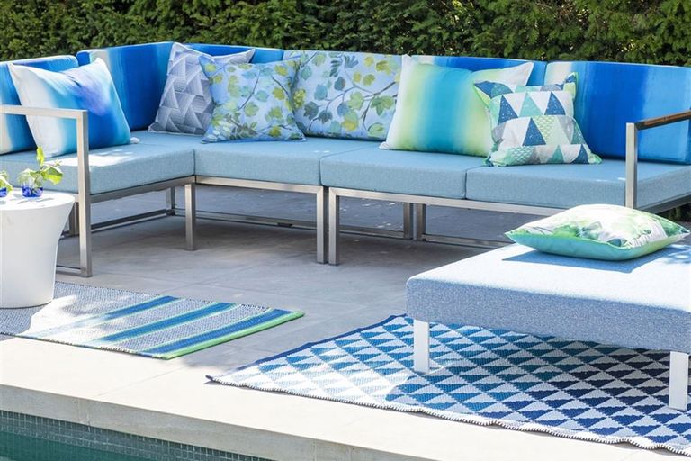 最好的户外地毯:蓝色装饰的户外地毯在花园背景与白色和蓝色户外家具
