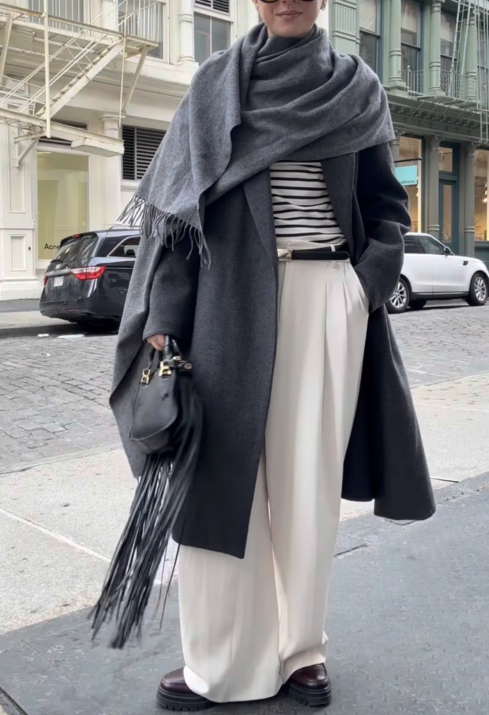 a photo of Jessica Habich Thomas wearing a draped coat with wide leg pants and a striped tshirt