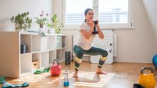 woman holds single dumbbell while performing a squat