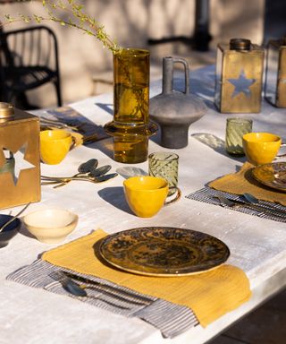 outdoor dining table with white linen table cloth and mustard accessories