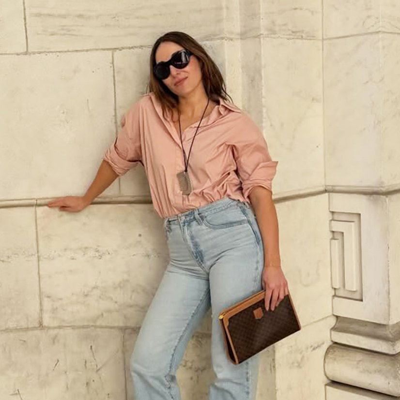 a woman wearing a pink button-down, light-wash straight-leg jeans, and white flats
