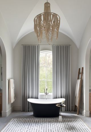 bathroom with off-white walls, vaulted ceilings, window and freestanding bath