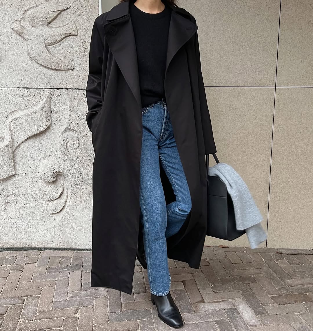 woman wearing slim jeans and black trench coat