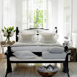 summer bedroom with colonial style dark wood bed with wooden shutters