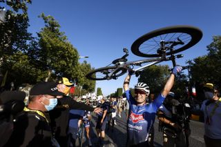 Jasper Philipsen holds his bike above his head on the Champs-Elysees at the Tour de France 2023