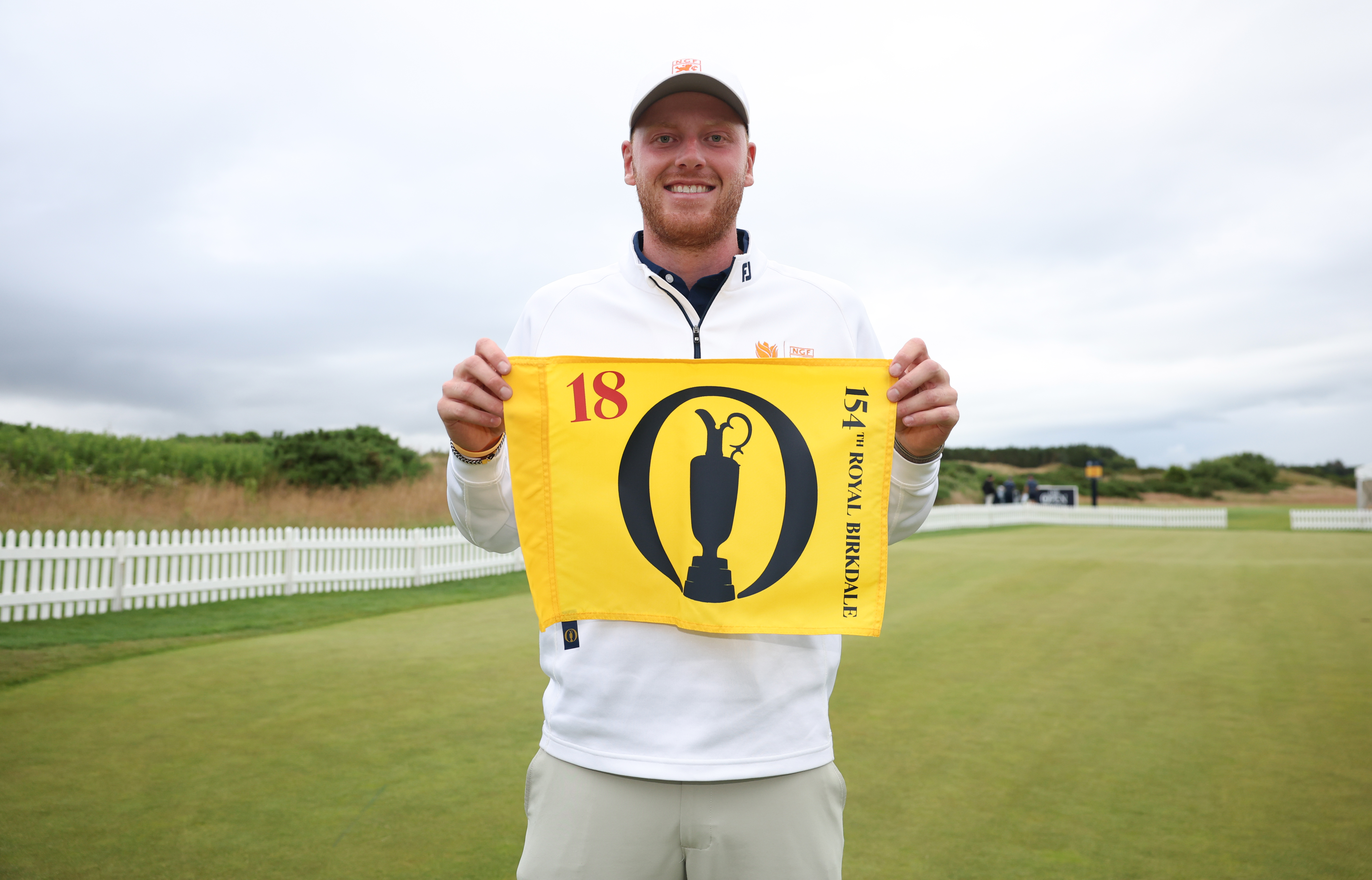Nevill Ruiter holds up The Open pin flag after qualifying for The 154th Open at Royal Birkdale at Dundonald Links Golf Course.
