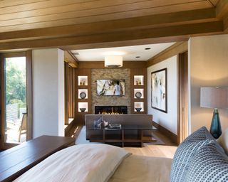 A bedroom TV idea with a television nook featuring a contemporary fireplace and seating