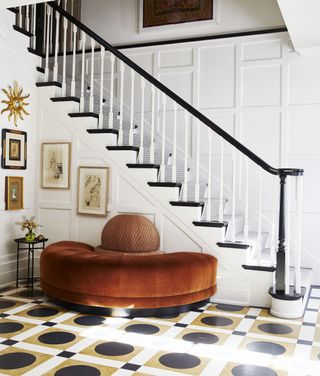 entryway with patterned floor tiles and orange curved sofa