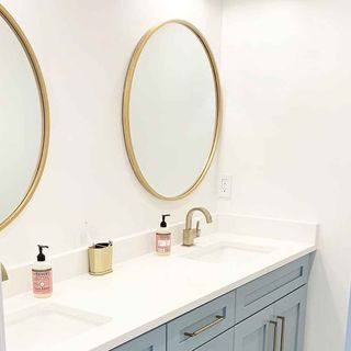 white bathroom with grey cabinet and white wash basin with large mirror