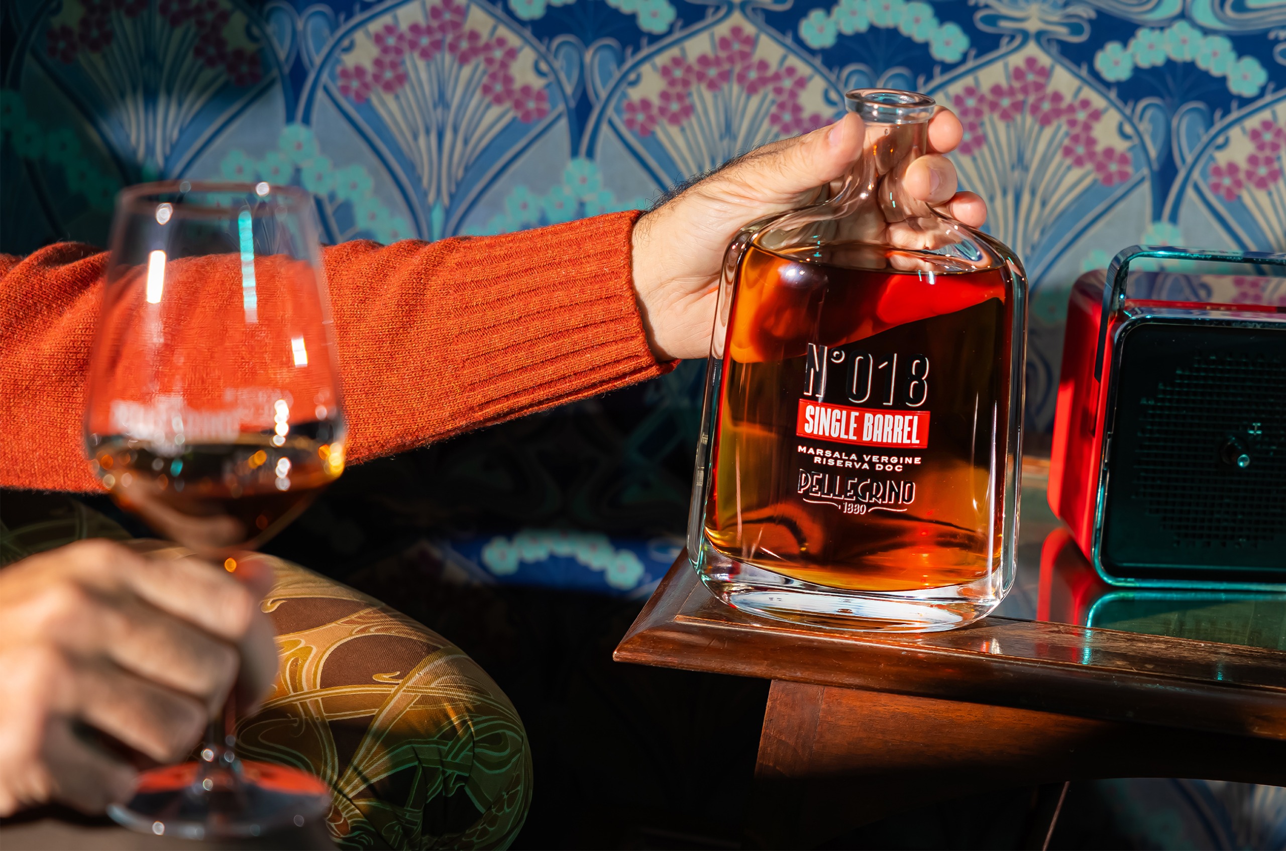 Bottle of Pellegrino single barrel, with a hand holding a glass