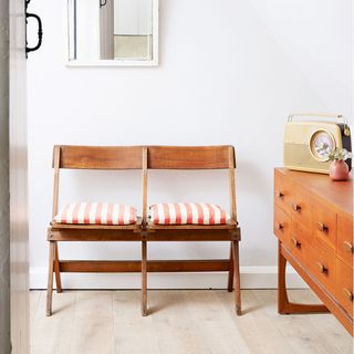 white room with retro chest and wooden bench with striped cushions