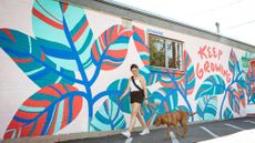 A woman and her dog walk in front of a colorful mural in Salt Lake City