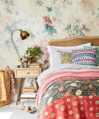 An example of guest bedroom ideas showing a colorful bedroom with a bed with a rattan headboard in front of colorful floral wallpaper