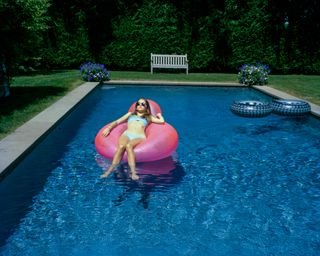 An image of a teenage girl sunbathing on a lilo in the middle of the pool