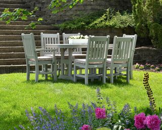 A garden table and chairs set on a lawn painted in a contemporary white color