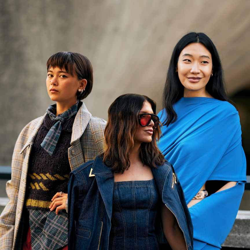 three women with brunette hair and stylish outfits