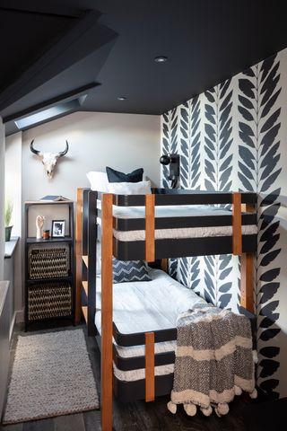 Kids' room with black and teak bunk beds, black painted ceiling, white walls and monochrome patterned feature wallpaper