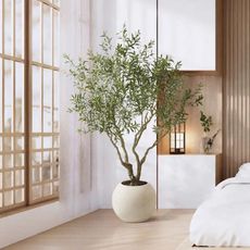 A faux olive tree in a modern white bedroom
