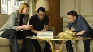 (L to R) Sarah Snook, Jeremy Strong and Kieran Culkin as Shiv, Kendall and Roman Roy, sitting around a table they're looking down at in Succession season 4 episode 4