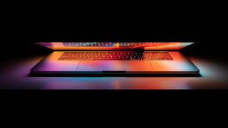 A laptop half-closed against a black backdrop
