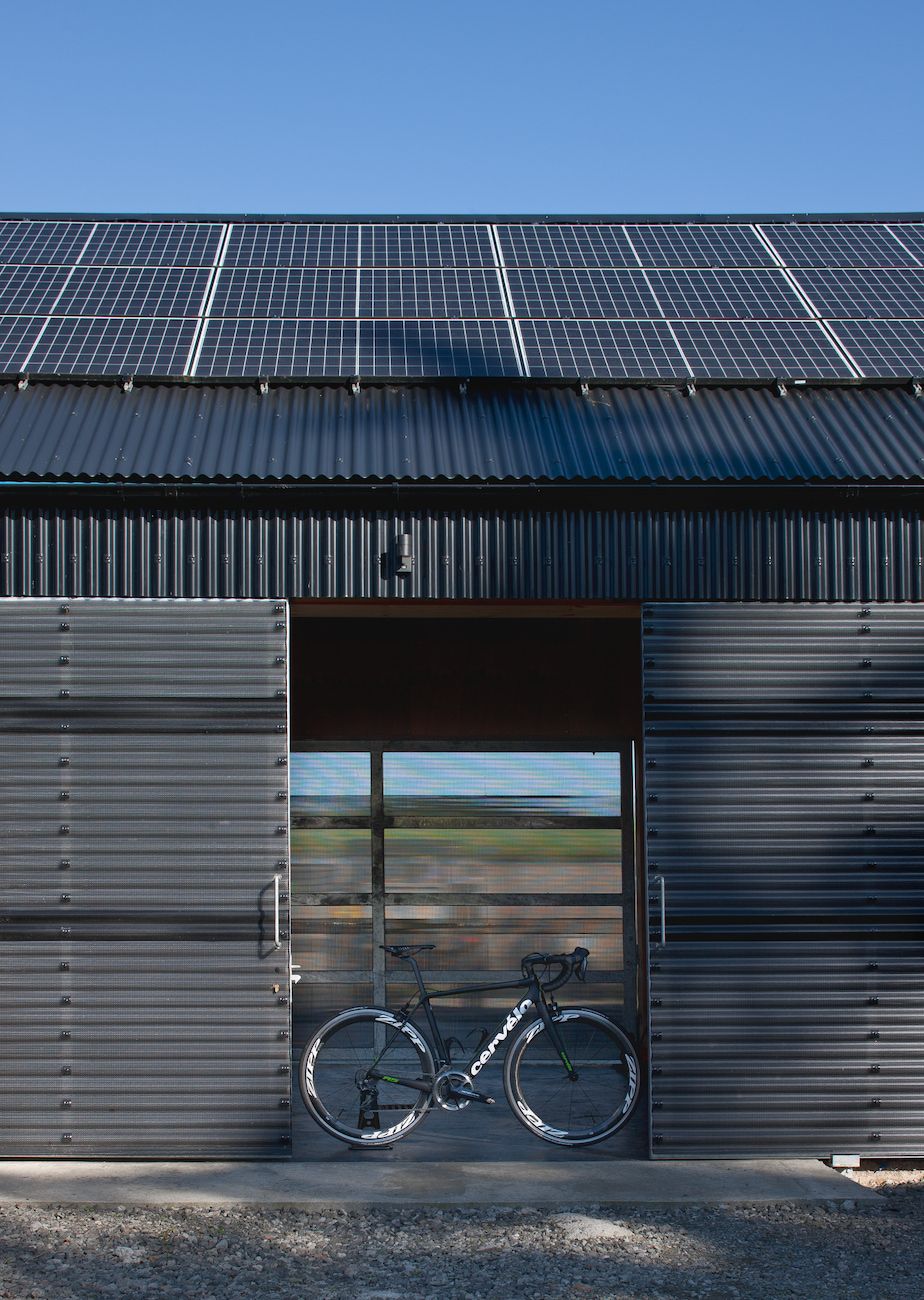The exterior of a corrugated metal clad home with bicycle leaning against the door