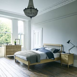 bedroom with blue wall wooden bed wooden drawer and wooden flooring