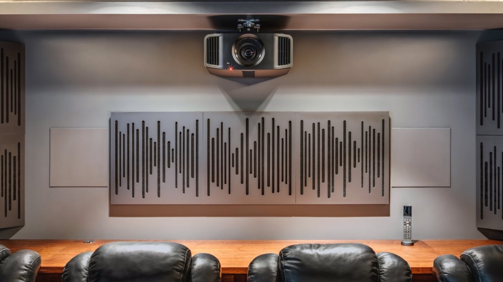 A photo of a custom-installed home cinema room featuring a 4K projector, theatre seating and clever acoustic treatment