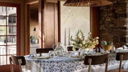 A dining table with a blue and white tablecloth in a dark, wooden room