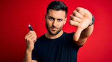 A man holding a USB-A flash drive in one hand and giving a big thumbs down gesture with the other.