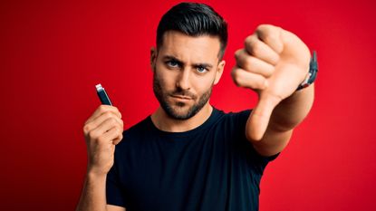 A man holding a USB-A flash drive in one hand and giving a big thumbs down gesture with the other.