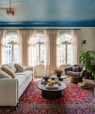 blue wallpapered ceiling in living room with white sofa and vintage rug