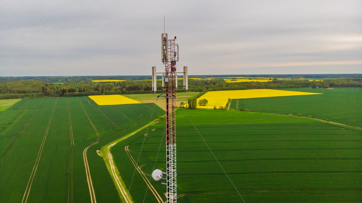 Aerial view video of telecommunication tower in the countryside farming fields with 4G, 5G cellular network antennas.