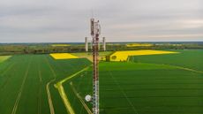 Aerial view video of telecommunication tower in the countryside farming fields with 4G, 5G cellular network antennas.