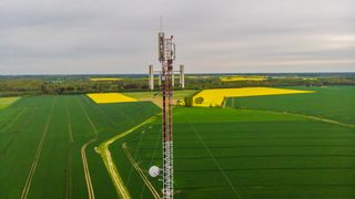 Aerial view video of telecommunication tower in the countryside farming fields with 4G, 5G cellular network antennas.