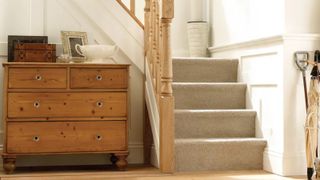 hallway with L shaped carpeted stairs and wooden spindles