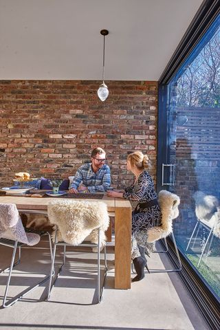 dining area next to a sliding door with brick-effect walls and sheepskin throws